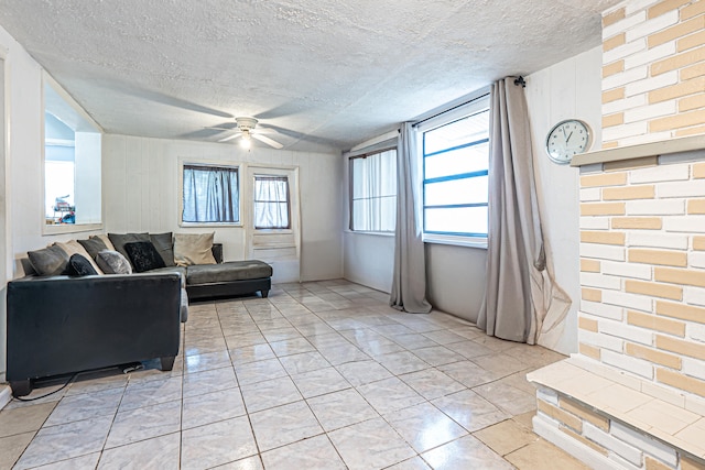 living room with ceiling fan, light tile patterned floors, and a textured ceiling