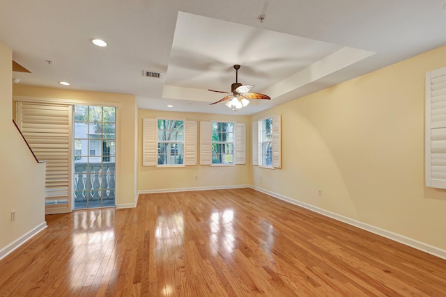 empty room featuring light hardwood / wood-style floors, a raised ceiling, and ceiling fan