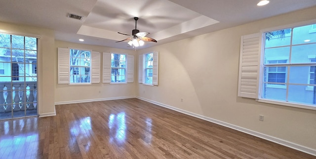 spare room with hardwood / wood-style flooring, a raised ceiling, and ceiling fan