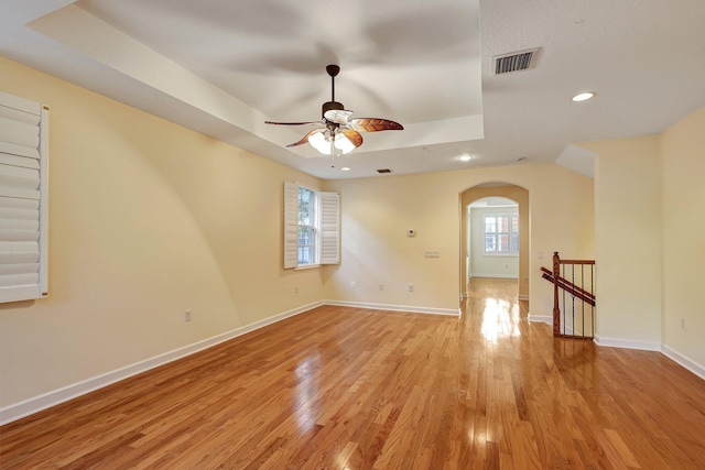 spare room with ceiling fan, a raised ceiling, and light hardwood / wood-style flooring