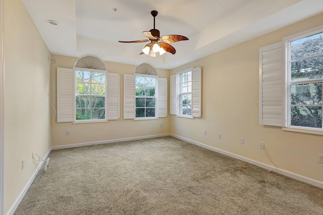 carpeted empty room with a tray ceiling and ceiling fan