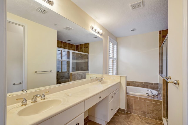 bathroom with tile patterned floors, vanity, shower with separate bathtub, and a textured ceiling