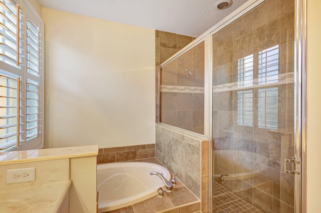 bathroom featuring a textured ceiling, independent shower and bath, and a healthy amount of sunlight