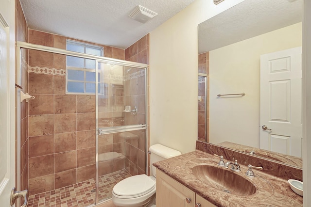 bathroom with vanity, toilet, a shower with door, and a textured ceiling