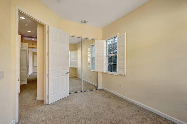 unfurnished bedroom featuring light carpet and a closet