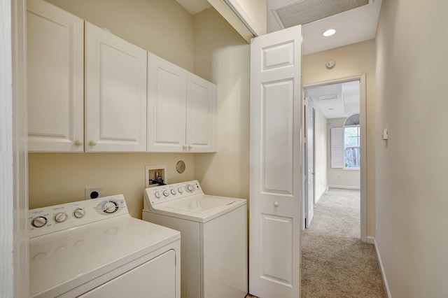 laundry room featuring separate washer and dryer, light carpet, and cabinets