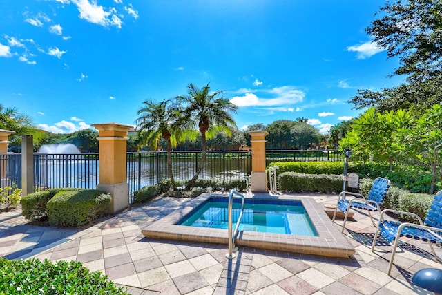 view of pool with an in ground hot tub, a water view, and a patio