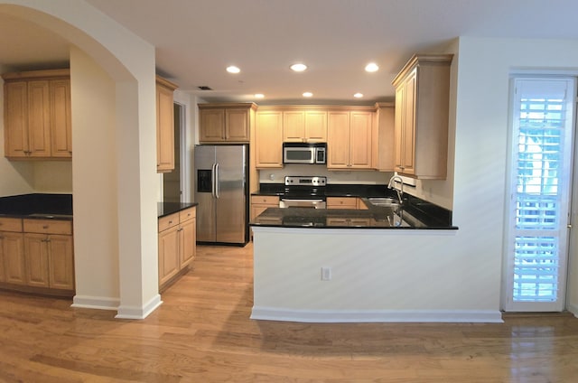 kitchen featuring kitchen peninsula, appliances with stainless steel finishes, sink, light brown cabinets, and light hardwood / wood-style flooring