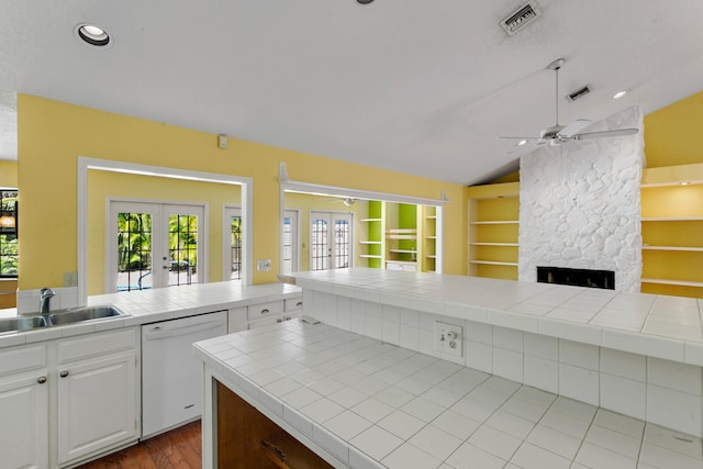 kitchen with french doors, white dishwasher, vaulted ceiling, tile countertops, and white cabinets