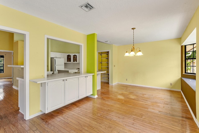 kitchen featuring decorative light fixtures, white cabinetry, white fridge, and light hardwood / wood-style flooring