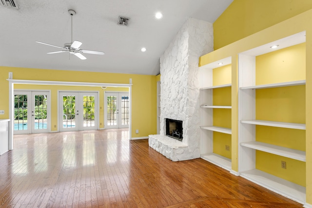 unfurnished living room featuring built in shelves, french doors, a healthy amount of sunlight, and hardwood / wood-style flooring