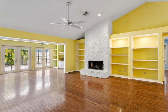 unfurnished living room with ceiling fan, french doors, built in features, wood-type flooring, and a fireplace