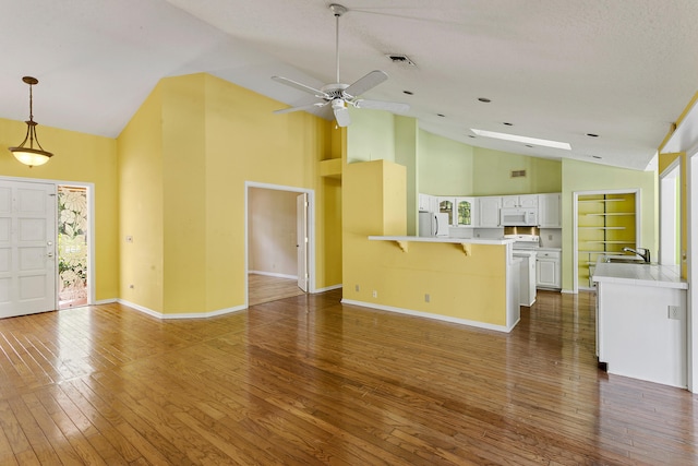 unfurnished living room with dark hardwood / wood-style flooring, a textured ceiling, sink, high vaulted ceiling, and built in features