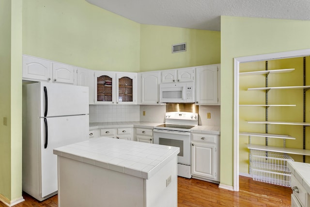 kitchen with tile countertops, white cabinetry, and white appliances