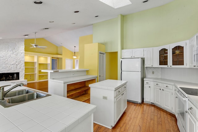 kitchen with light wood-type flooring, white appliances, sink, a center island, and white cabinetry