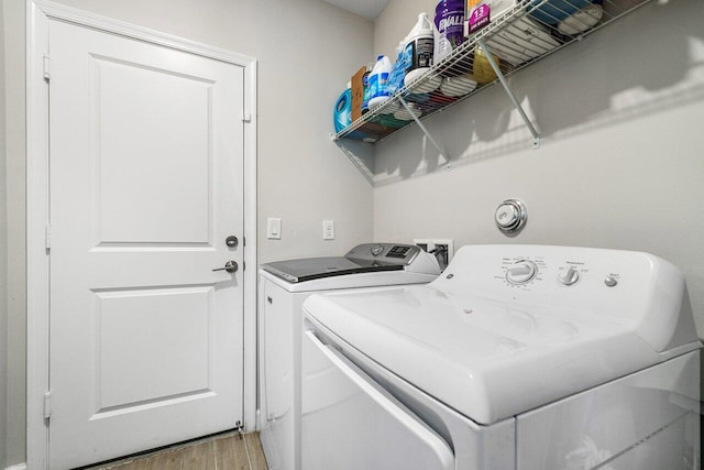 washroom with washing machine and dryer and hardwood / wood-style flooring