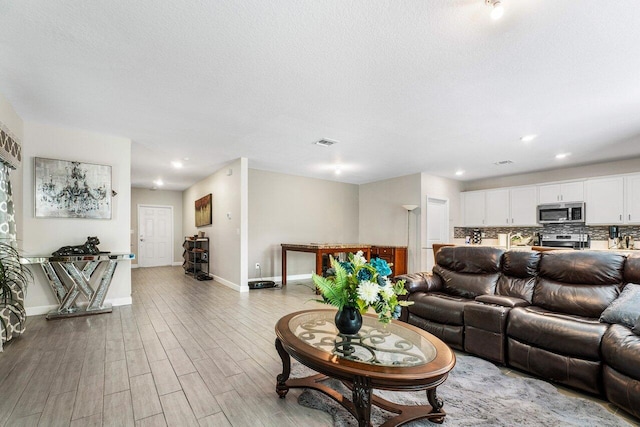 living room with light wood-type flooring and a textured ceiling