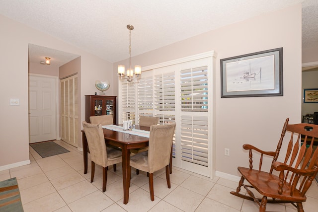 dining area with light tile patterned floors, a notable chandelier, a textured ceiling, and baseboards