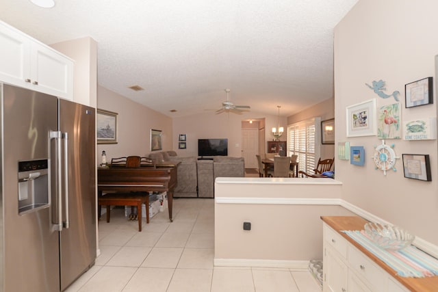 kitchen featuring light tile patterned flooring, lofted ceiling, white cabinets, and high end refrigerator