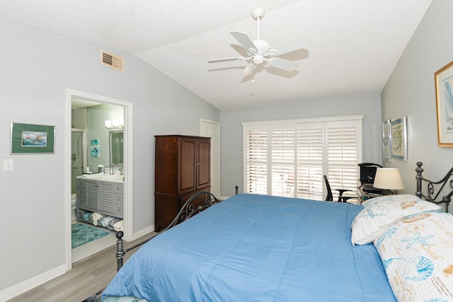 bedroom with visible vents, baseboards, lofted ceiling, ensuite bathroom, and wood finished floors