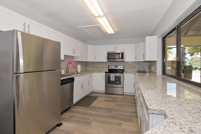 kitchen with a sink, decorative backsplash, appliances with stainless steel finishes, and white cabinetry