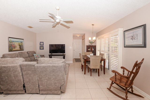 living room featuring vaulted ceiling, light tile patterned flooring, visible vents, and a textured ceiling