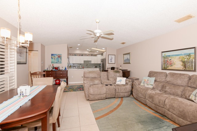 living area with vaulted ceiling, light tile patterned floors, visible vents, and a textured ceiling