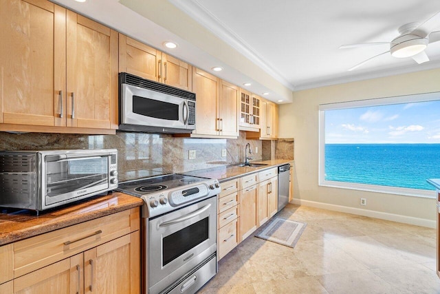 kitchen with a water view, decorative backsplash, ornamental molding, light brown cabinetry, and appliances with stainless steel finishes