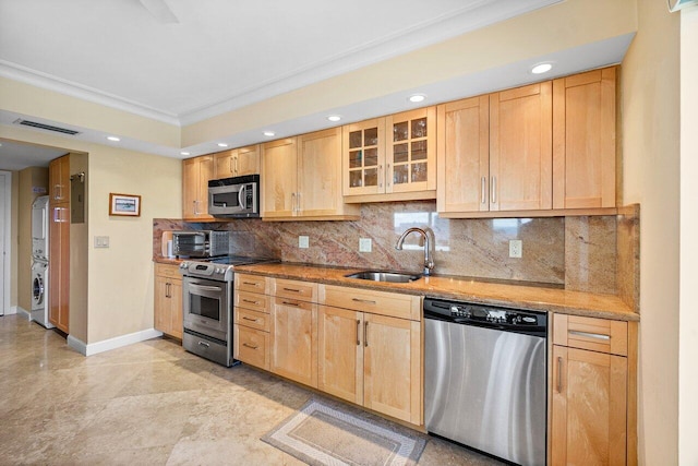 kitchen with stainless steel appliances, crown molding, sink, light brown cabinets, and stacked washer / dryer