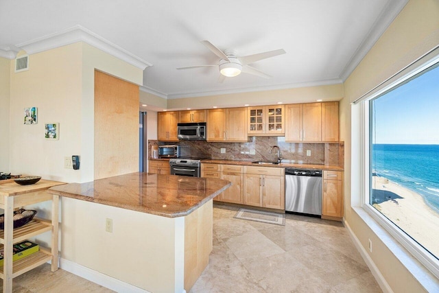 kitchen with stone countertops, stainless steel appliances, a healthy amount of sunlight, and a water view