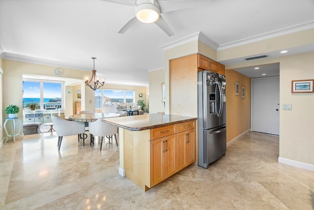 kitchen with hanging light fixtures, stainless steel refrigerator with ice dispenser, dark stone countertops, crown molding, and ceiling fan with notable chandelier