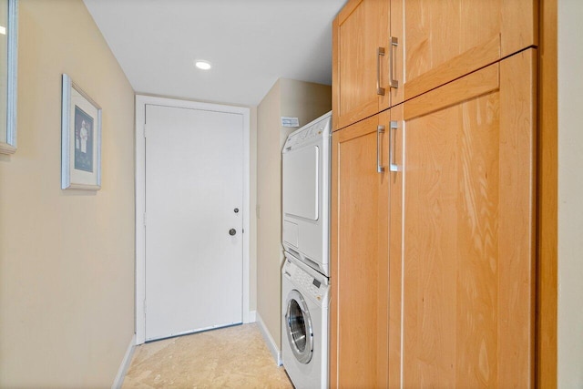 laundry room featuring stacked washer / dryer and cabinets