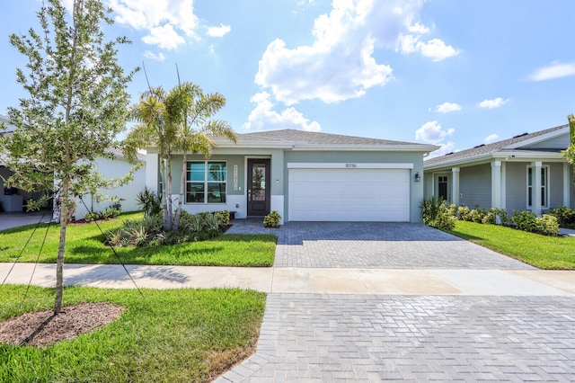 single story home featuring stucco siding, an attached garage, decorative driveway, and a front yard