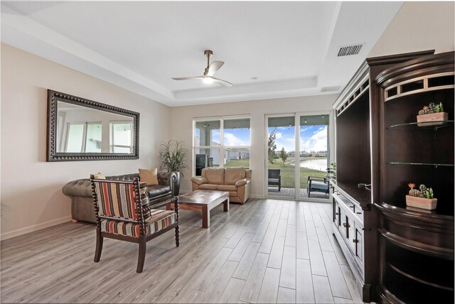 sitting room featuring light hardwood / wood-style floors, ceiling fan, and a tray ceiling