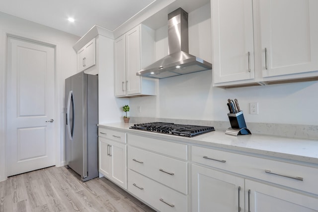 kitchen featuring white cabinets, wall chimney exhaust hood, light stone countertops, and appliances with stainless steel finishes