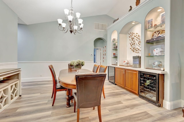 dining area featuring wine cooler, built in features, a chandelier, light hardwood / wood-style floors, and lofted ceiling