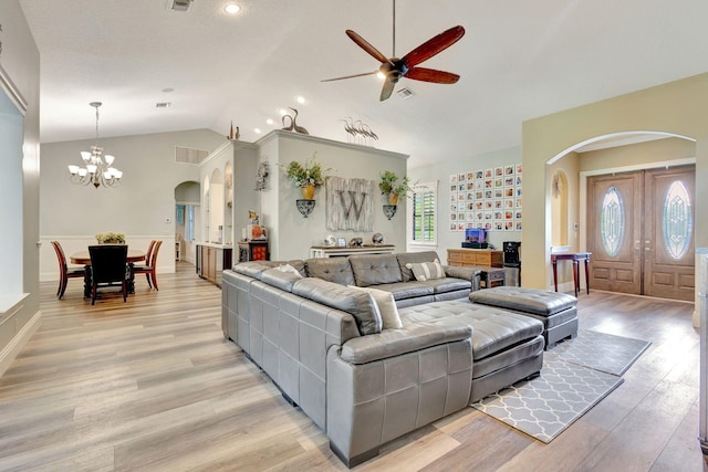 living room featuring lofted ceiling, ceiling fan with notable chandelier, and light wood-type flooring