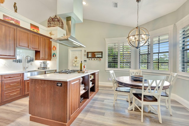 kitchen featuring an inviting chandelier, hanging light fixtures, light hardwood / wood-style flooring, a kitchen island, and island exhaust hood