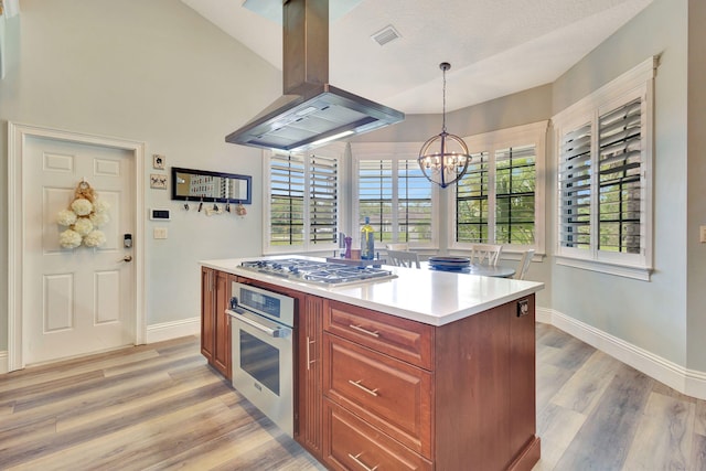 kitchen featuring a textured ceiling, decorative light fixtures, island range hood, appliances with stainless steel finishes, and light wood-type flooring