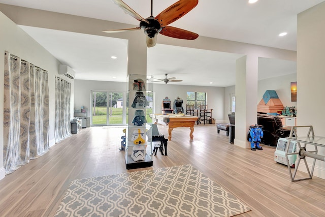 living room with an AC wall unit, billiards, and light hardwood / wood-style flooring