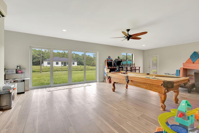 playroom with a wall mounted AC, light wood-type flooring, ceiling fan, and pool table