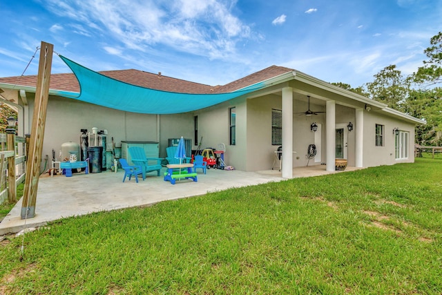 back of property featuring ceiling fan, a patio, and a lawn