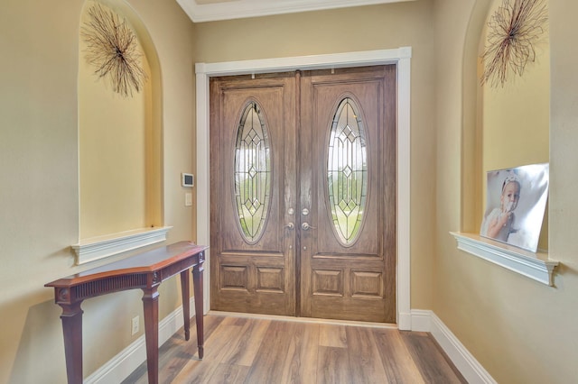 entryway with hardwood / wood-style floors and crown molding