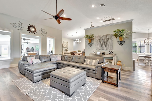 living room with hardwood / wood-style floors, ceiling fan with notable chandelier, and lofted ceiling