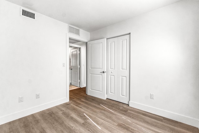 unfurnished bedroom featuring hardwood / wood-style floors and a closet