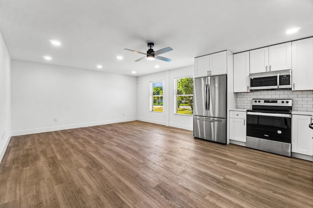 kitchen with white cabinets, hardwood / wood-style flooring, ceiling fan, tasteful backsplash, and stainless steel appliances