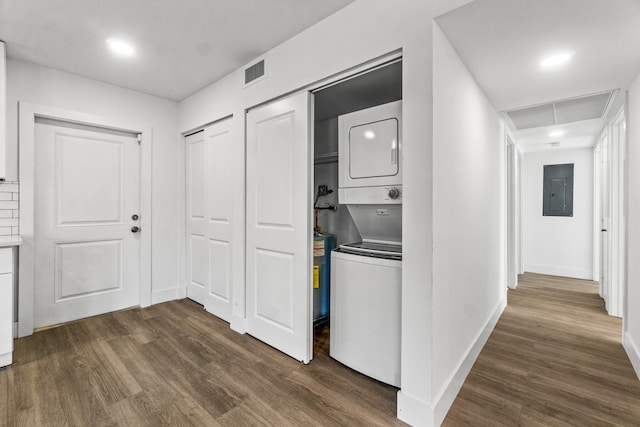 washroom featuring electric panel, dark hardwood / wood-style floors, and stacked washer and clothes dryer