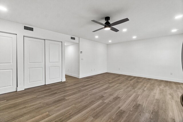 unfurnished bedroom with multiple closets, ceiling fan, and hardwood / wood-style floors