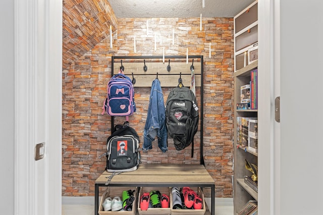 mudroom featuring a textured ceiling and lofted ceiling