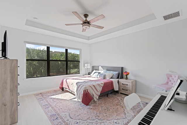 bedroom featuring a tray ceiling, light hardwood / wood-style flooring, and ceiling fan